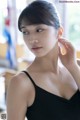 A woman in a black dress is putting on her earrings.