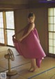 A woman in a pink dress standing in front of a fan.