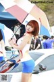 A woman holding an umbrella standing next to a car.