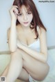 A woman in a white lingerie sitting on the floor.