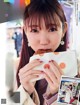 A woman eating a piece of food in front of a magazine.