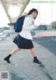 A woman in a school uniform is walking down the street.